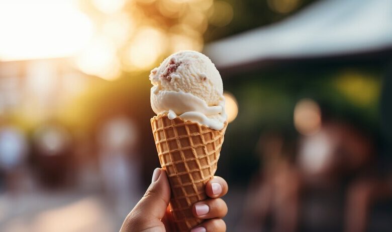 A person holding a cone ice cream outside an ice cream shop