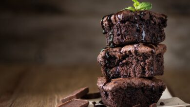 A stack of 3 perfect chocolate brownie with a mint leaf on it