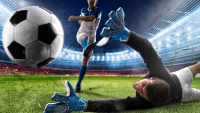 Football players kicking the football and keeper diving to grab the ball showcasing expensive football tickets