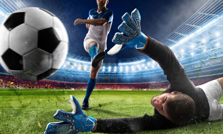 Football players kicking the football and keeper diving to grab the ball showcasing expensive football tickets